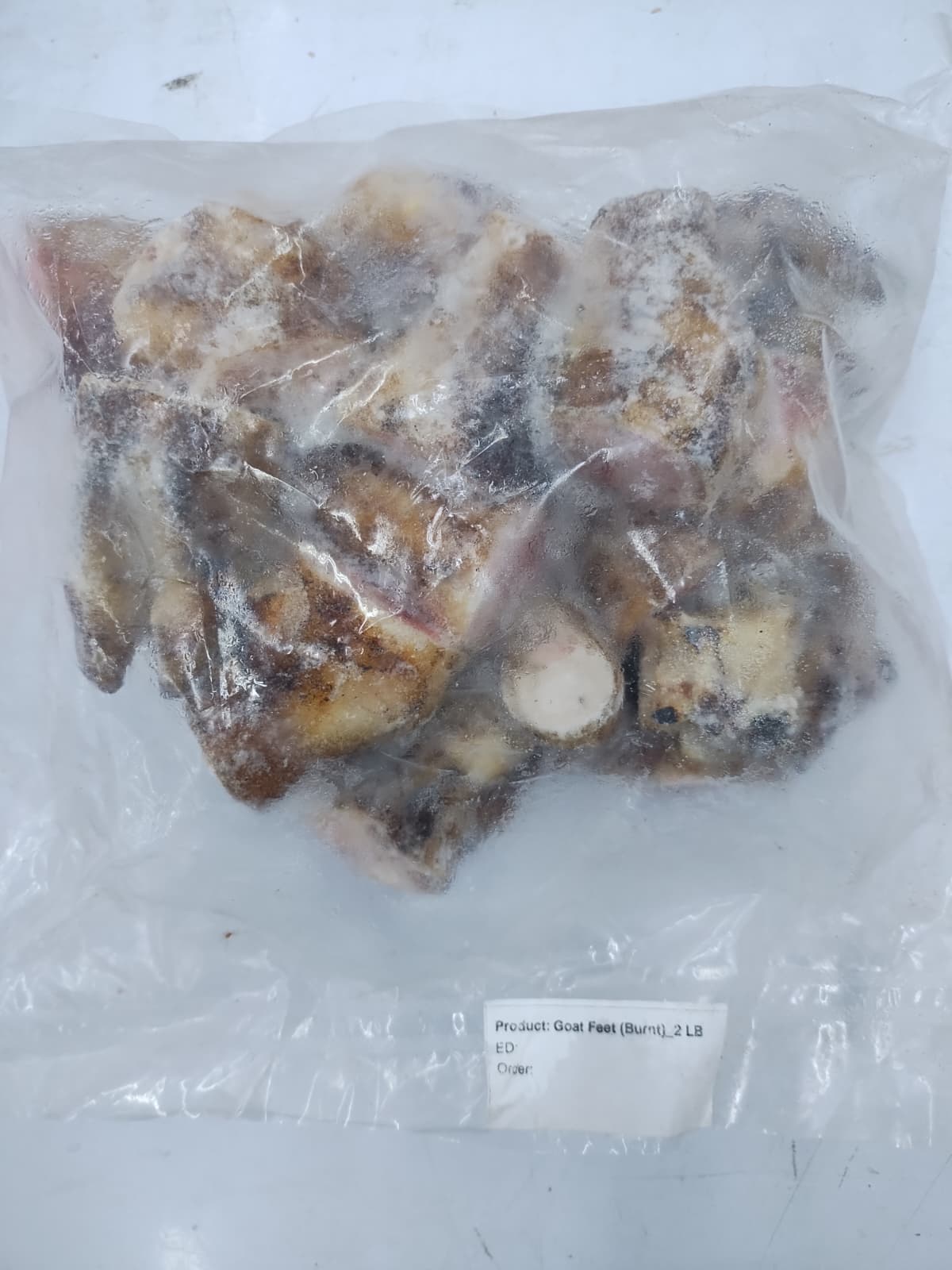 Bag of frozen burnt goat feet on a white background