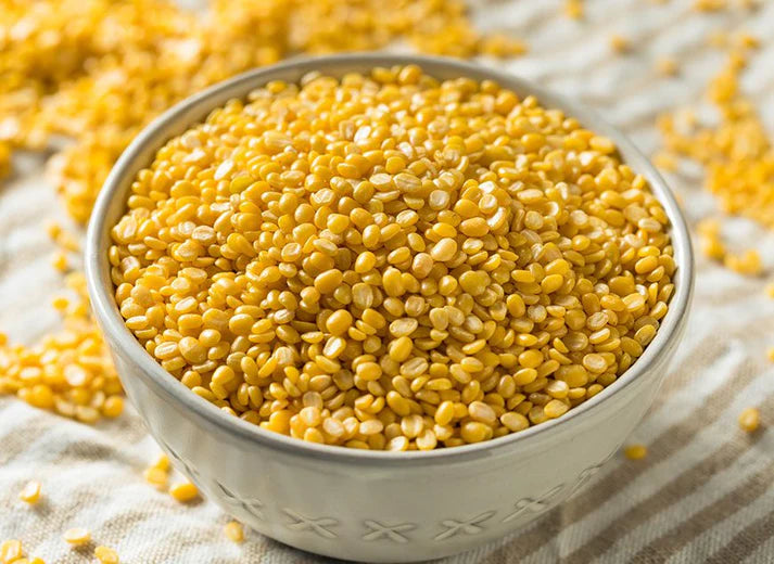 Yellow moong dal in a white bowl on a textured surface