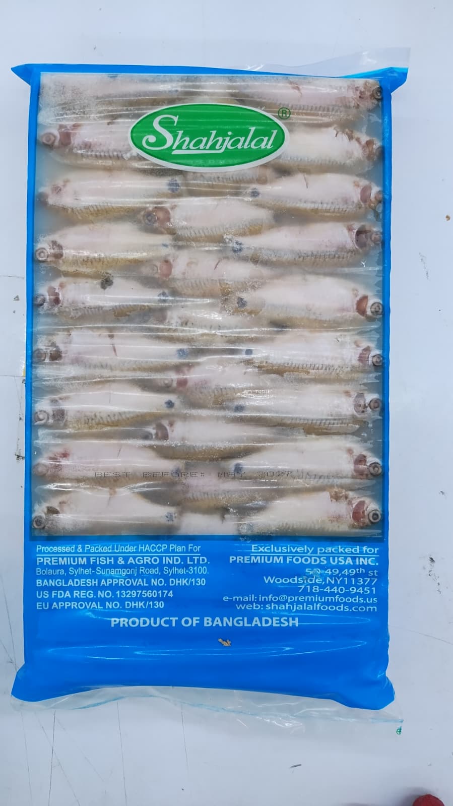 A packaged frozen Puti fish in a clear plastic bag with a bright blue border and a green oval Shahjalal logo at the top, showing rows of Puti fish inside. Text on the package includes 'Product of Bangladesh' and 'Premium Fish & Agro Ind.