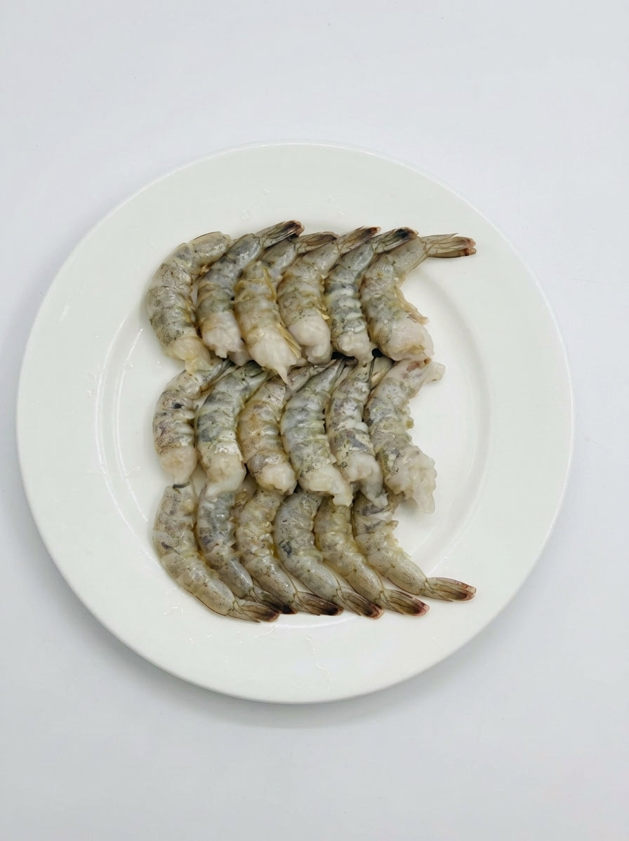 Raw shrimp prawns arranged on a white oval plate against a plain white background.
