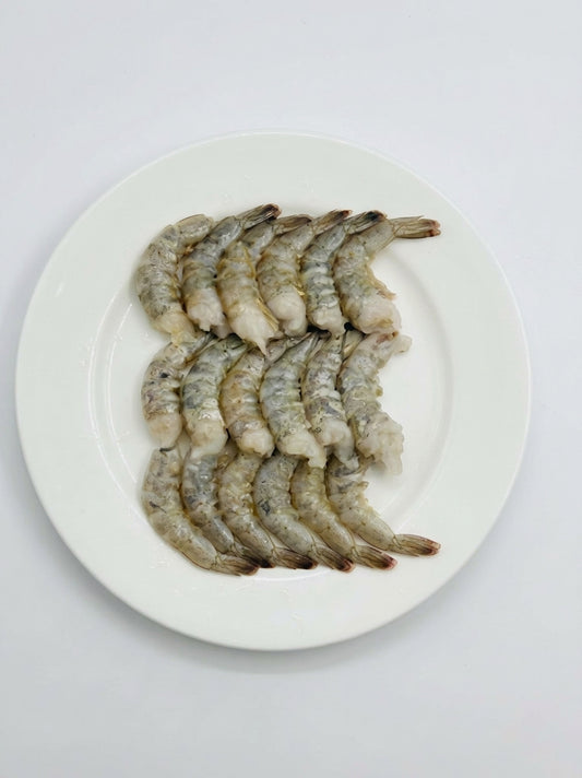 Raw shrimp prawns arranged on a white oval plate against a plain white background.