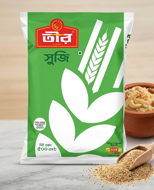 A package of Tuir Suji (wheat flour) in a green and white bag, displayed on a marble surface with a bowl of prepared suji dish and a wooden spoon of loose flour in the background.