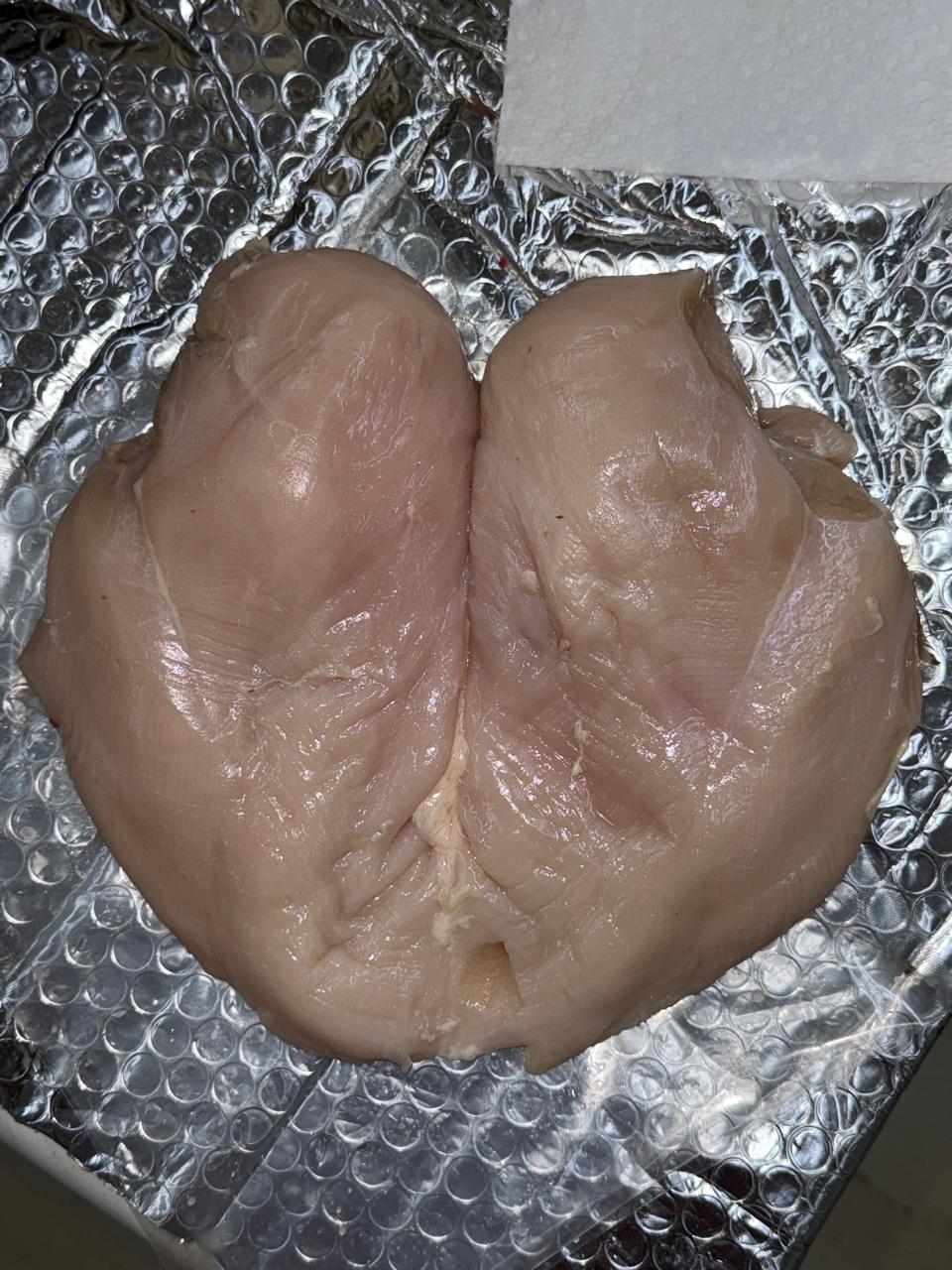 Raw  Zabiha Halal chicken breast cutlets placed on silver bubble wrap packaging.