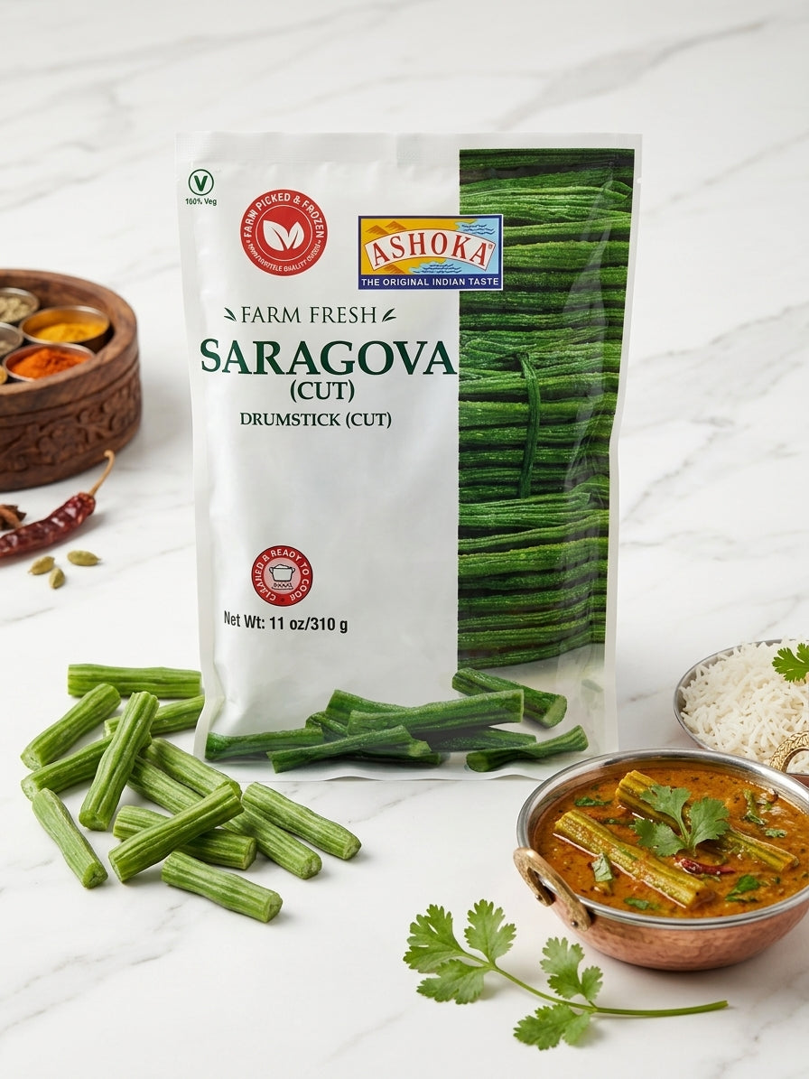 A package of Ashoka Farm Fresh Saragova (cutoff) drumstick (cut) in a white stand-up pouch with a green vegetable photo on the front, styled on a white marble surface with loose green drumsticks, a bowl of curry, and garnishes.