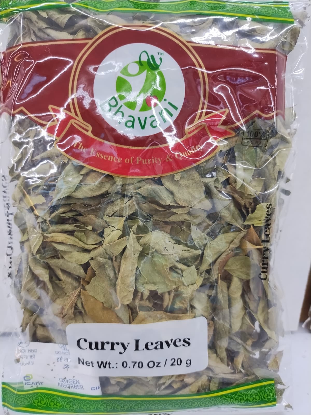 A clear plastic bag of Bhavani brand dried curry leaves, showing the light tan-green leaves inside with a red and green brand label and a white label at the bottom.