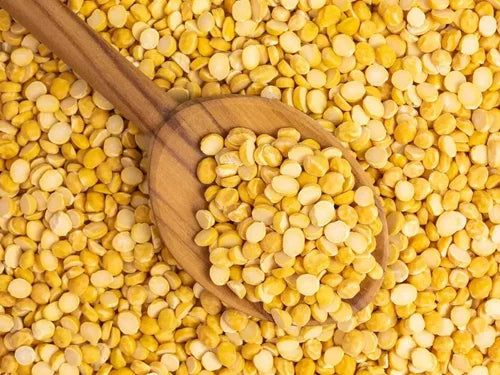 Yellow split peas with a wooden spoon on a bed of yellow split peas