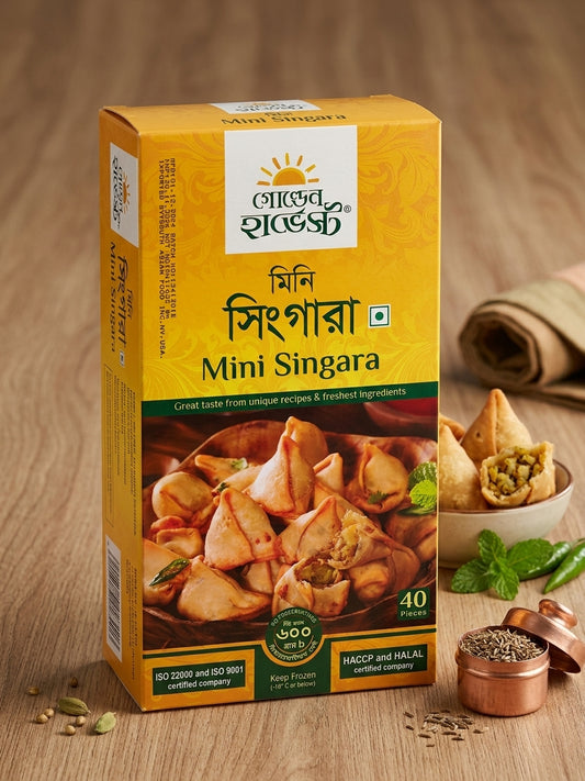 A box of golden harvest Mini Singara (Indian samosa filling mix) displayed on a wooden table alongside fresh ingredients like mint leaves, green chilies, and spices.