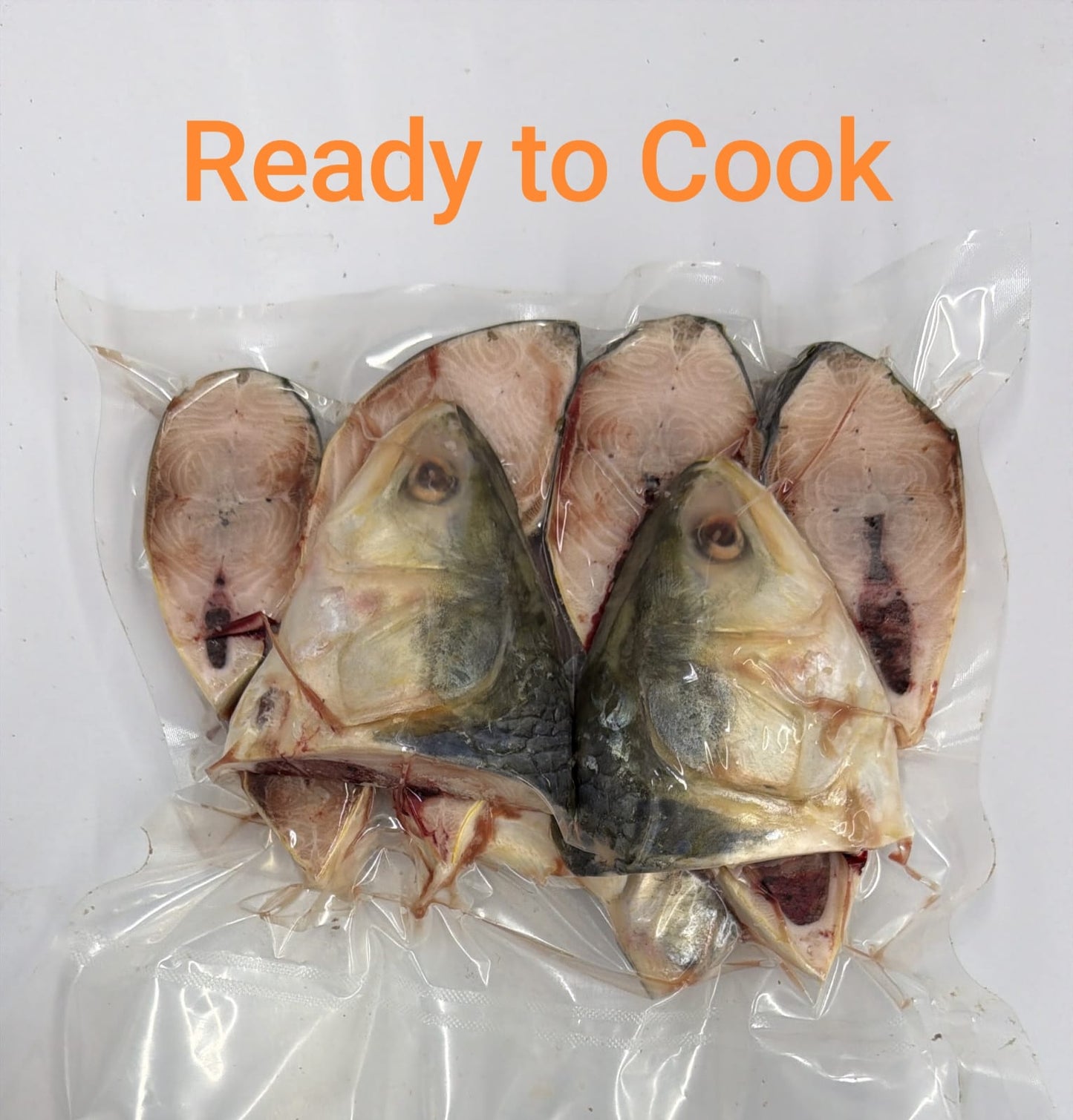 Four raw fish heads and fillets sealed in a clear plastic vacuum bag, with orange text reading 'Ready to Cook' at the top on a white background.