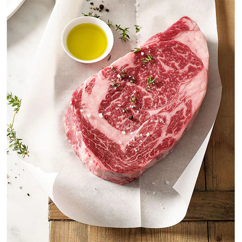 Raw steak with oil and herbs on a wooden surface